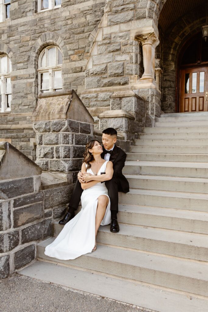bride and groom sitting on stairs together in front of a historic building