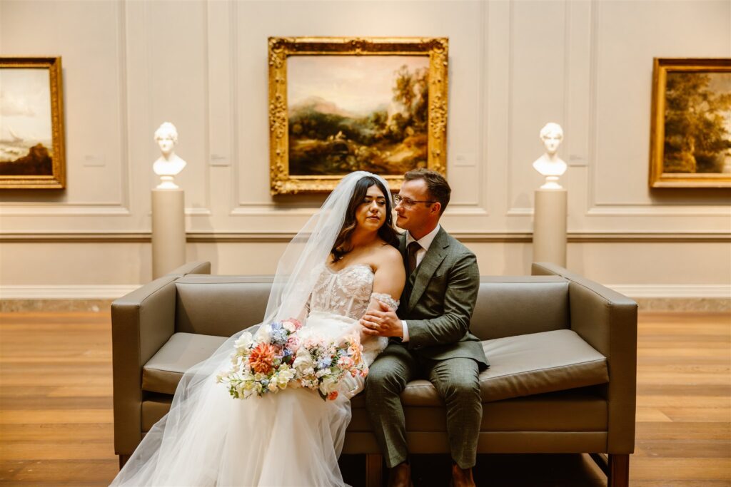 bride and groom sitting on the sofa in front of the gorgeous artwork at the national gallery of art