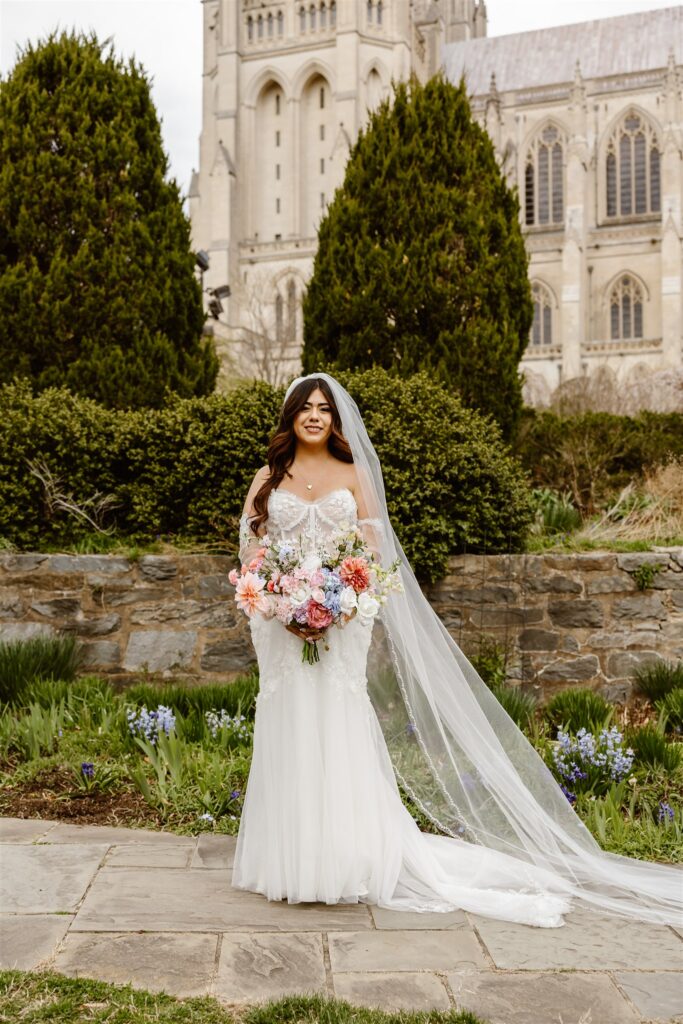bride at the national cathedral gardens during their dc cherry blossom wedding day