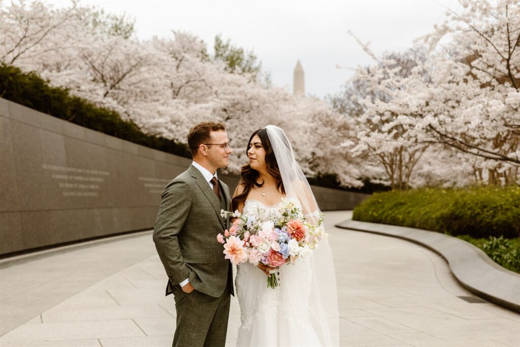 romantic bride and groom exploring tidal basin during their dc cherry blossom wedding 