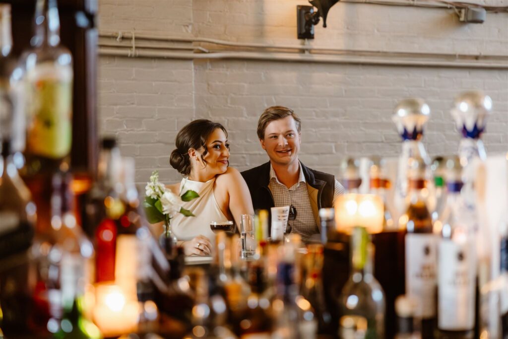 bride and groom sitting at a cocktail bar together