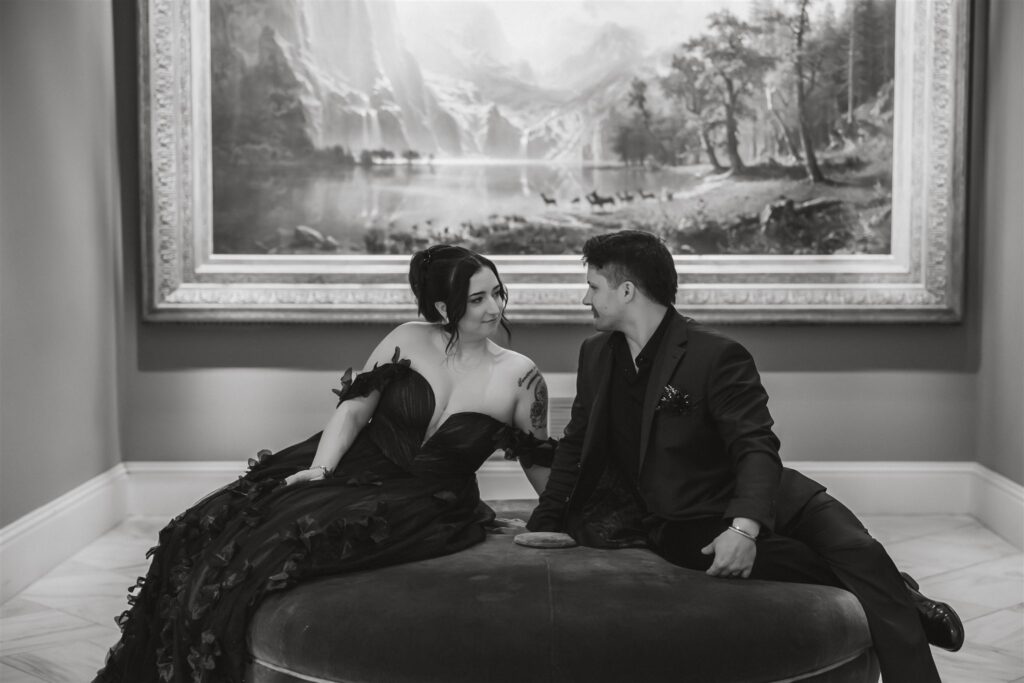 bride and groom sitting in front of a painting at the national portrait gallery 