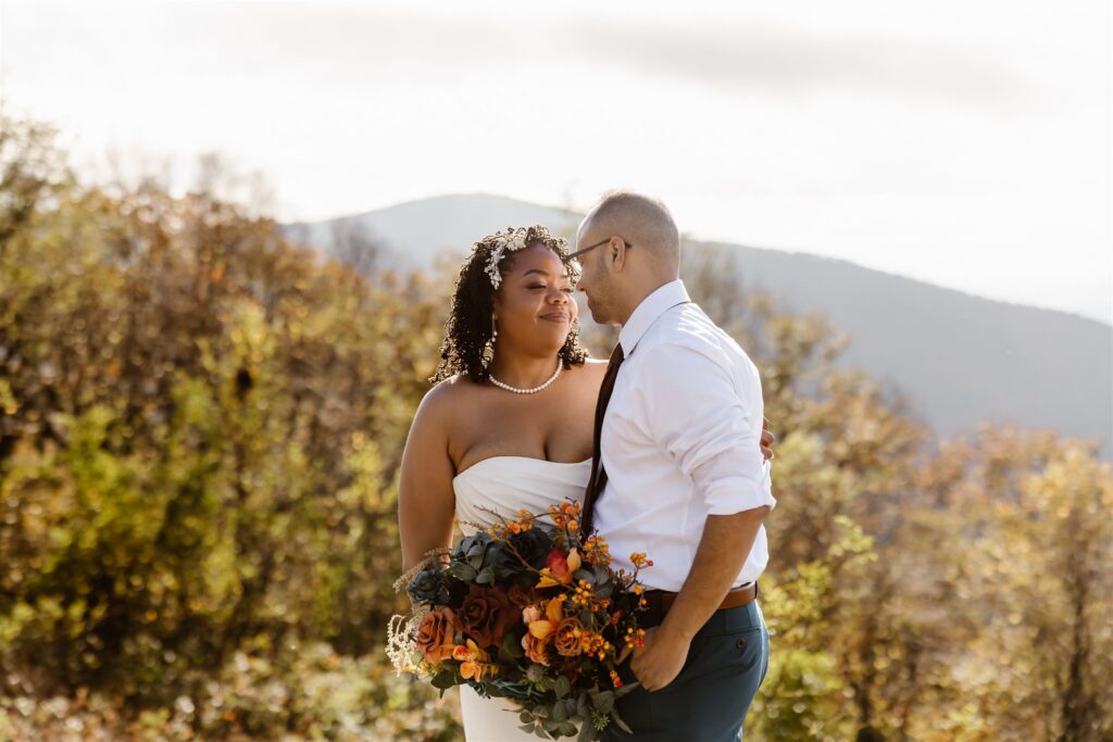 adventurous elopement couple snuggling at a mountain overlook in shenandoah national park