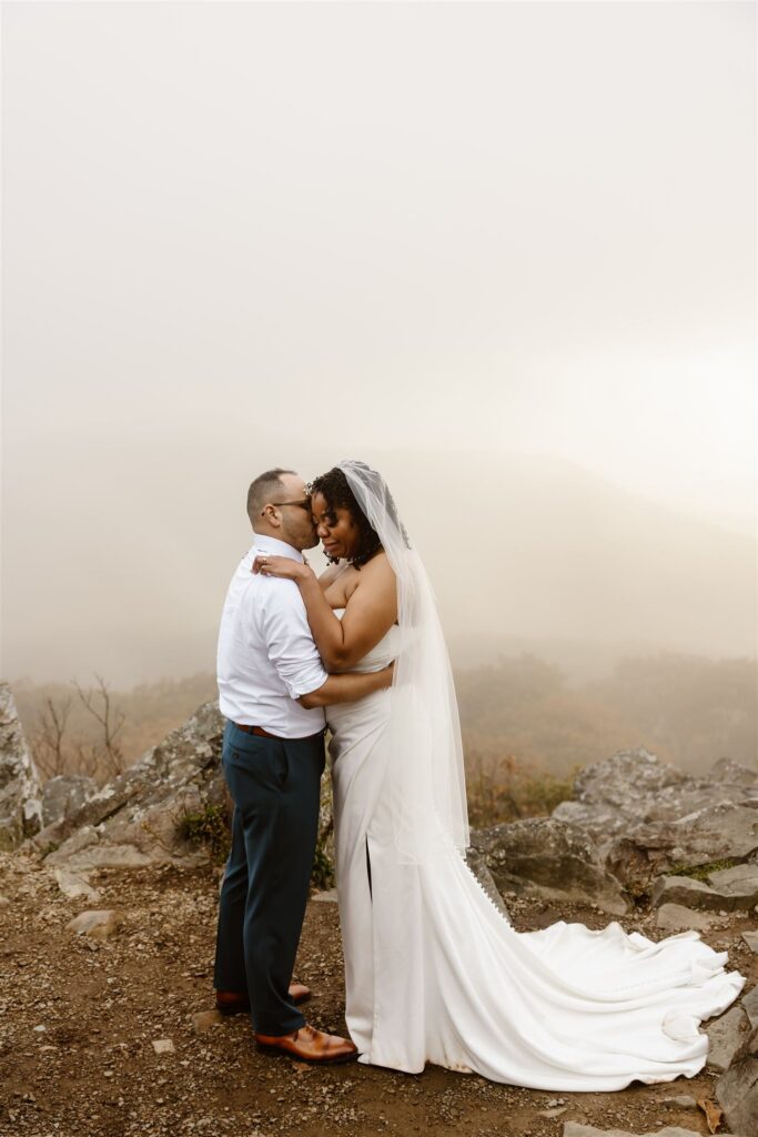 adventurous elopement couple snuggling at a mountain overlook in shenandoah national park