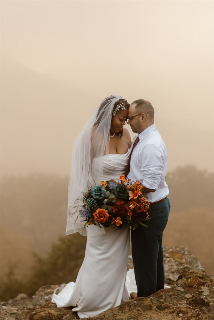 adventurous elopement couple snuggling at a mountain overlook in shenandoah national park