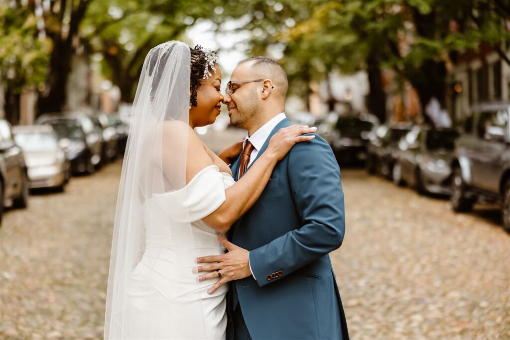 bride and groom kissing with cozy cobblestone street in the backdrop