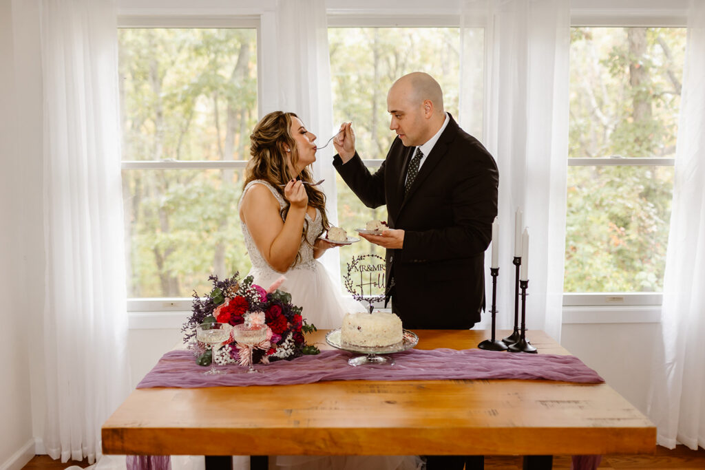bride and groom sharing a small elopement cake inside a cozy airbnb