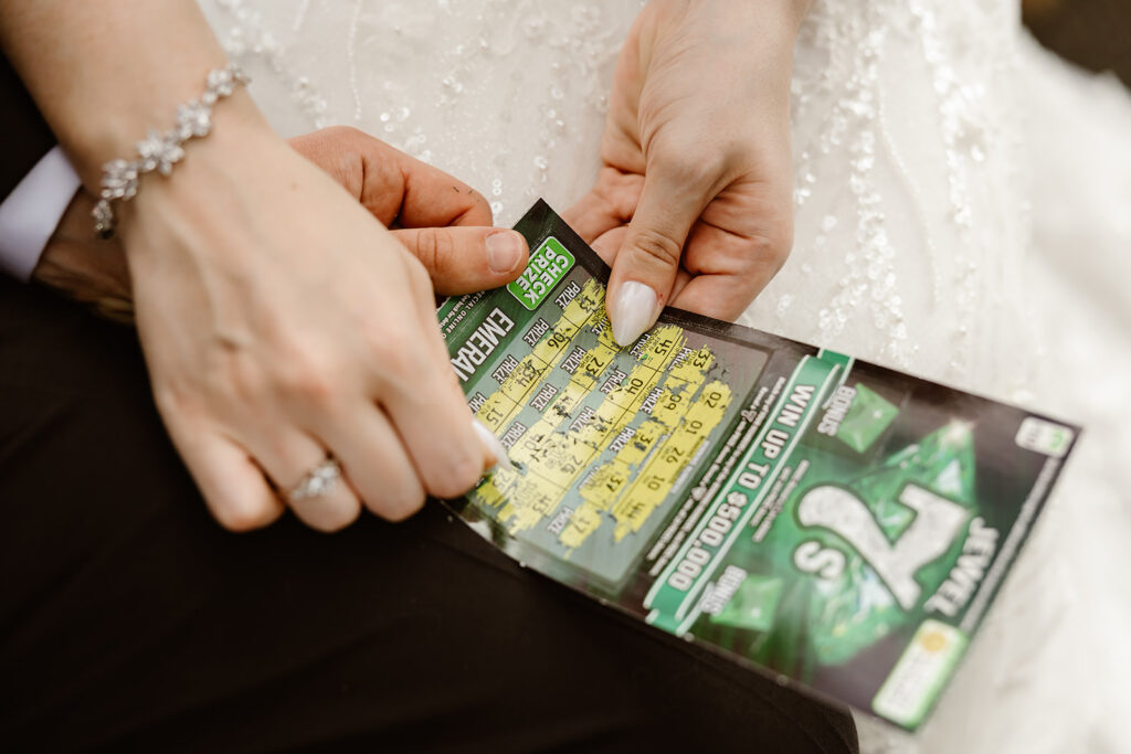 bride and groom scratching off lottery tickets together at a mountain overlook in shenandoah national park