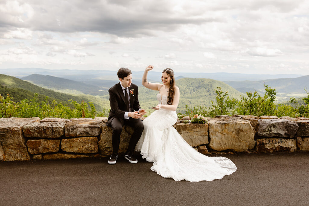 bride and groom scratching off lottery tickets together at a mountain overlook in shenandoah national park
