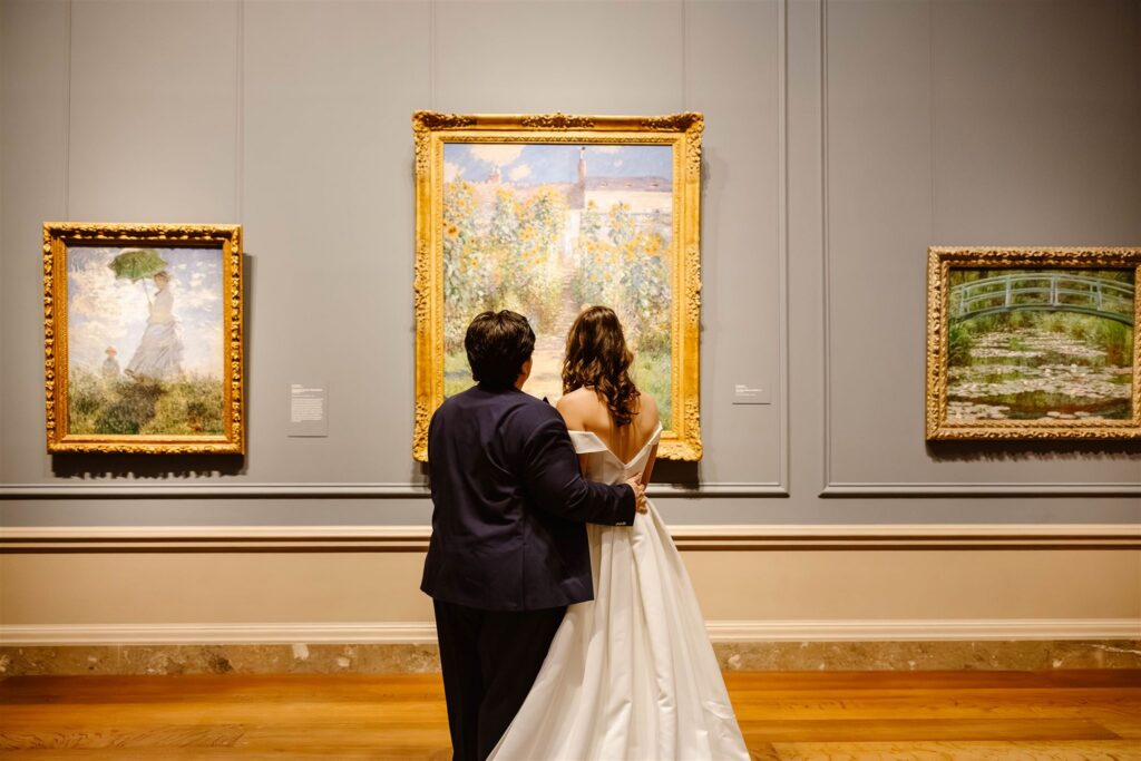 the wedding couple standing by a painting at the art museum