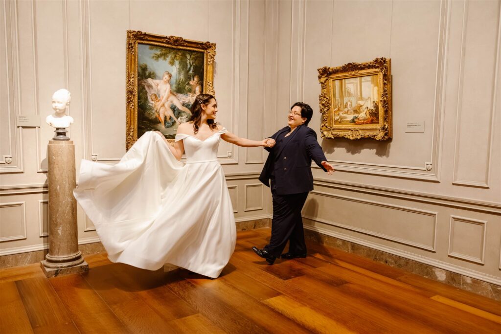 the wedding couple dancing by a painting at the art museum