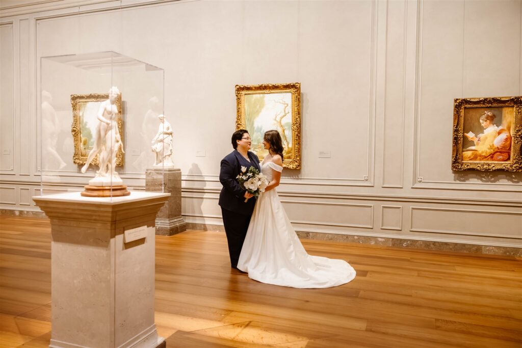 the wedding couple kissing by a painting at the art museum