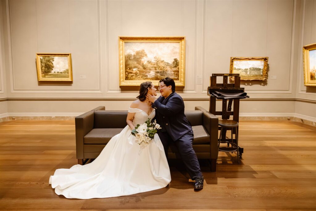 the wedding couple kissing by a painting at the art museum