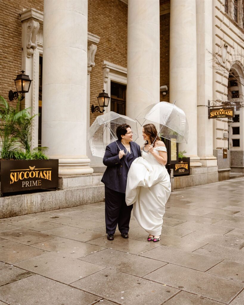 elopement couple under clear umbrellas in front of succotash prime