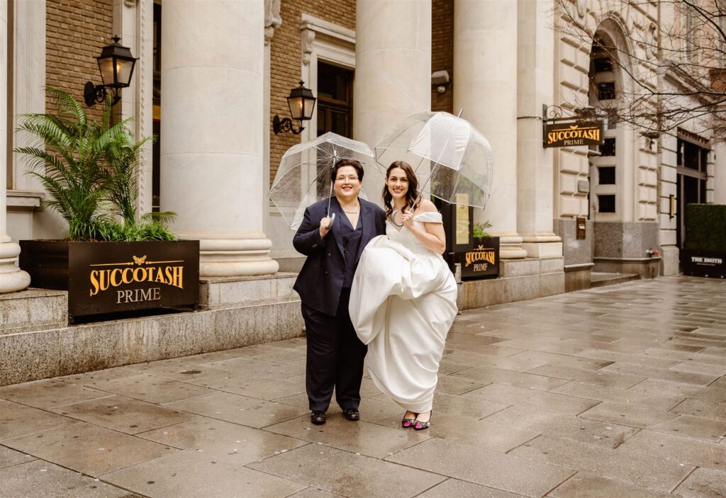 elopement couple under clear umbrellas in front of succotash prime