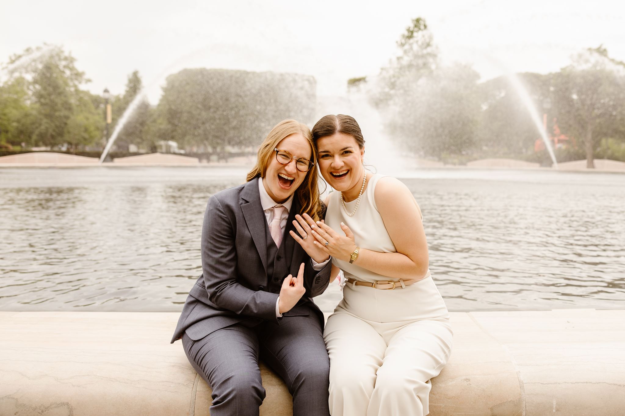 excited elopement couple sitting in front of a fountain at constitution gardens in dc