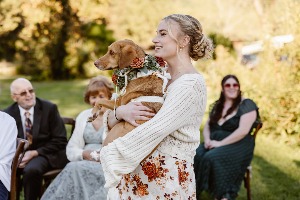 dog getting carried down the aisle as a flower girl
