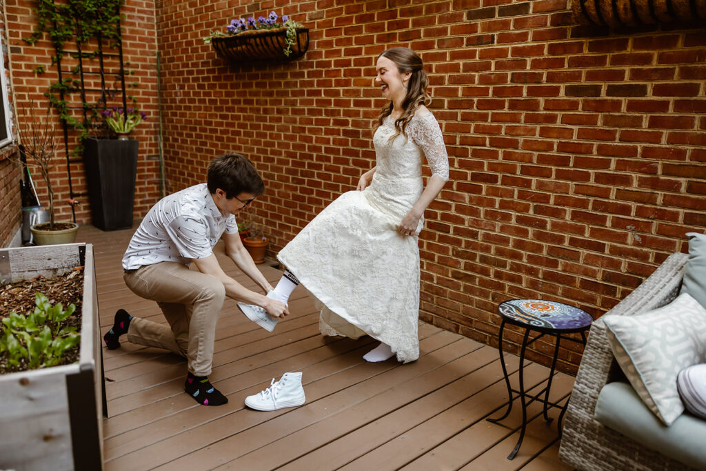 friend helping the bride put on sneakers