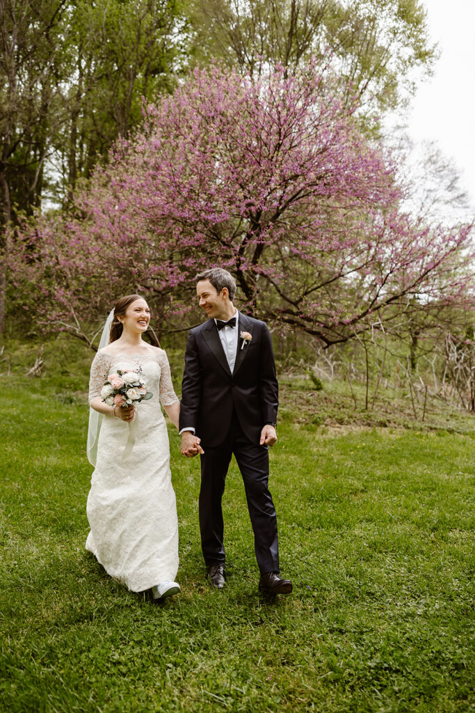 elopement couple walking hand in hand in front of a pink blossoming tree