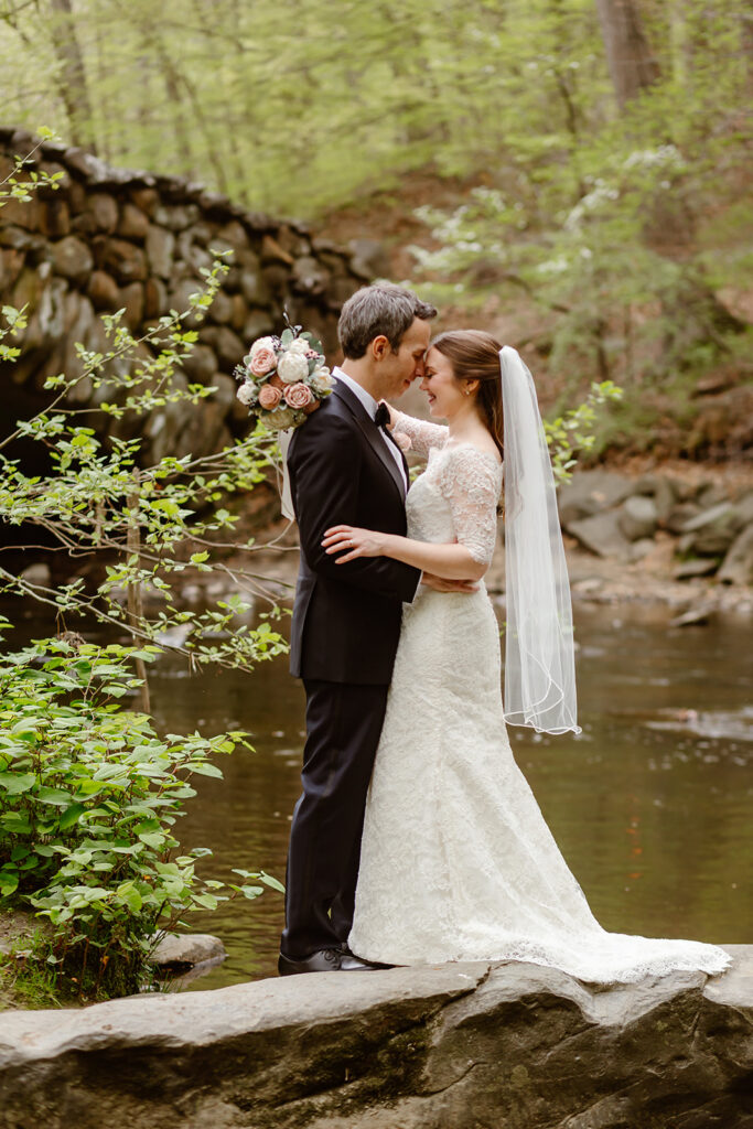 joyful elopement couple at rock creek park posing in front of an old stone bridge