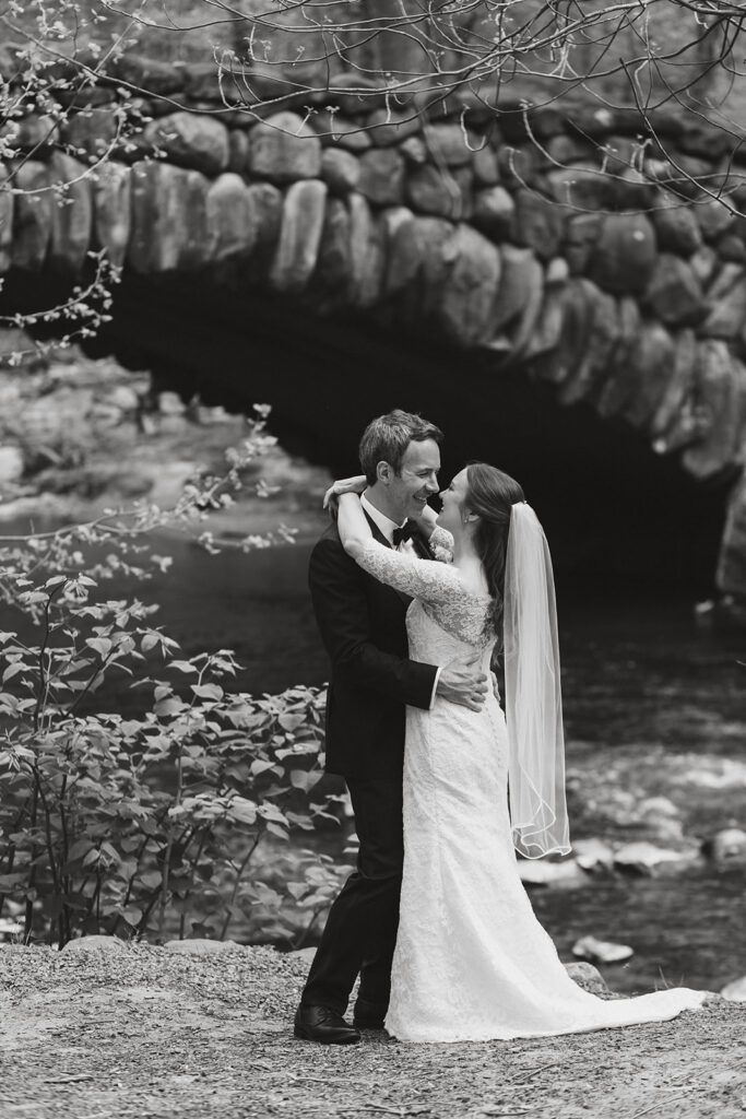 joyful elopement couple at rock creek park posing in front of an old stone bridge